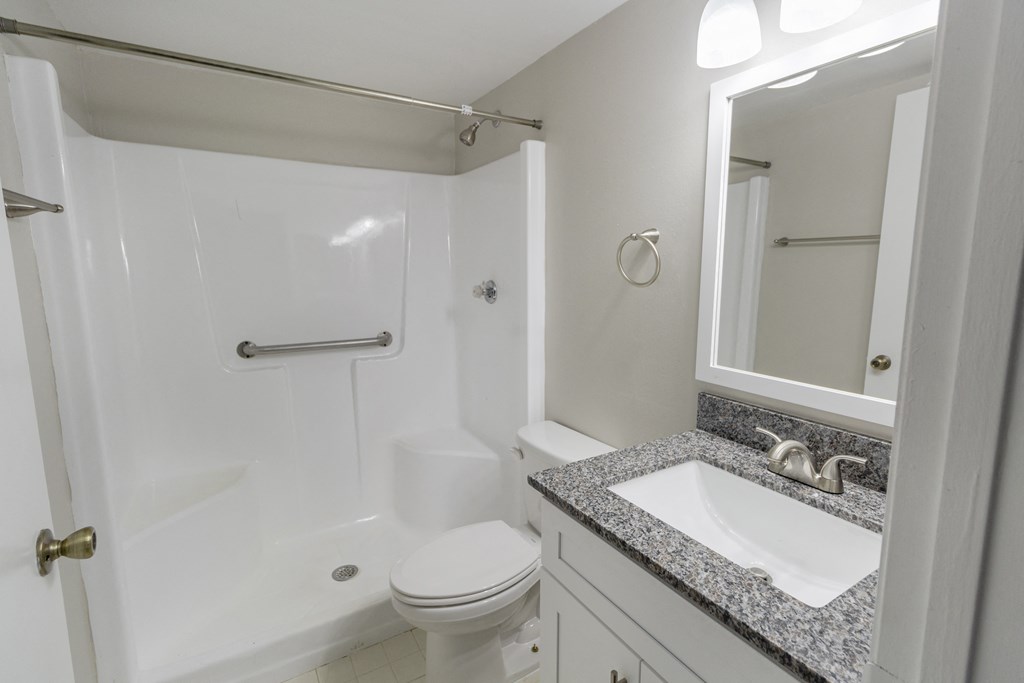 A white bathroom with a toilet, sink and shower.